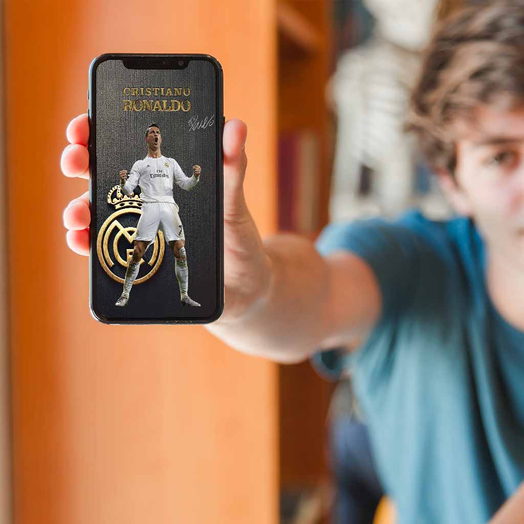 Fan holding smartphone displaying Cristiano Ronaldo digital sports art — a high-resolution mobile-ready printable wall art download.