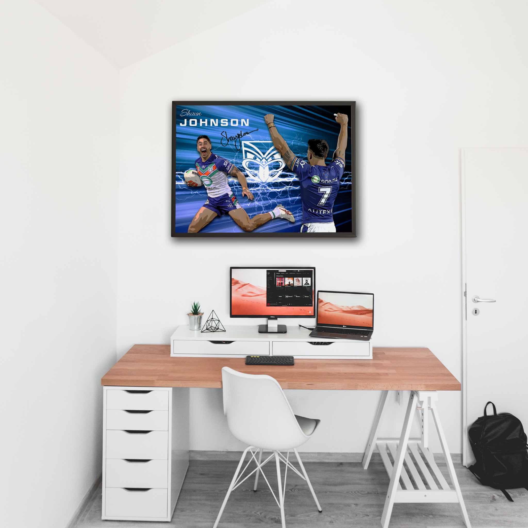 New Zealand Warriors fan office with a framed print of Shaun Johnson hung on the wall above the computer screen.