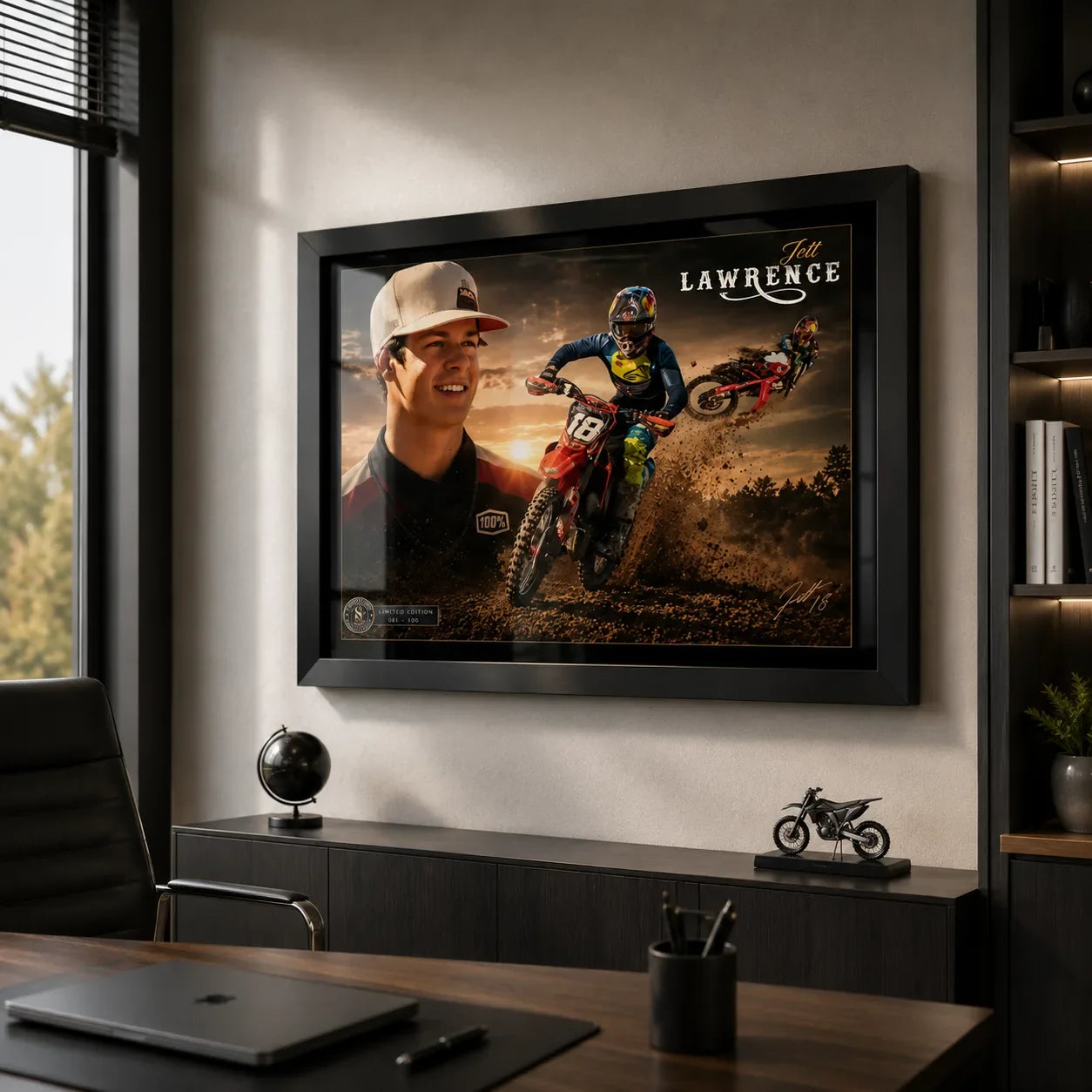 Black framed Jett Lawrence motocross wall art displayed behind a desk in a modern office with neutral walls.