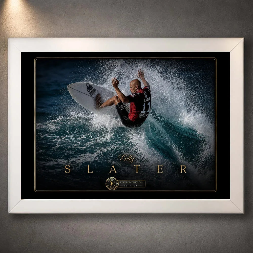 White framed Kelly Slater surfing wall art showing his turn through a breaking wave in a black and gold collector design.
