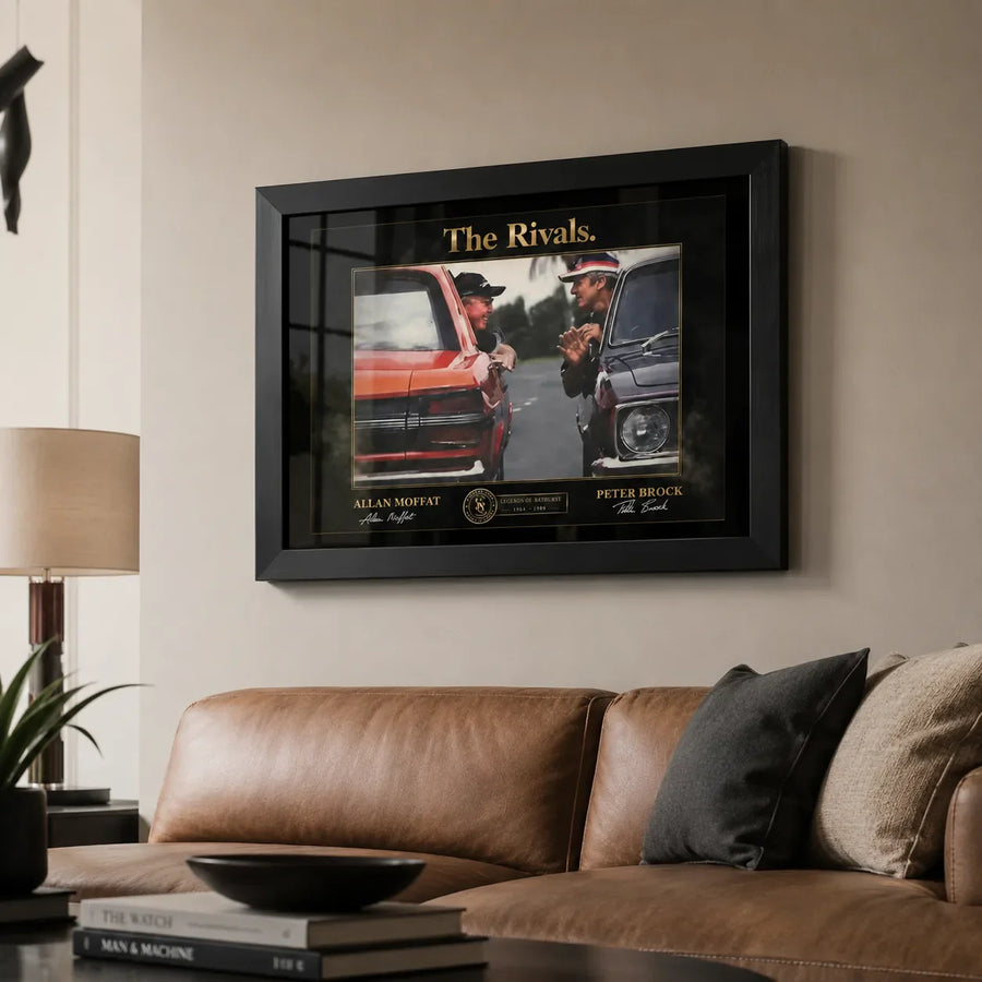 Framed motorsport rivalry wall art displayed in a premium living room above a neutral sofa