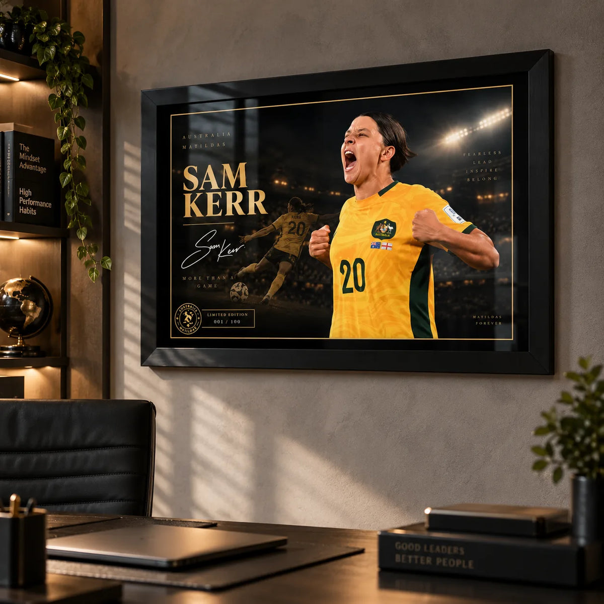Black framed Sam Kerr Matildas soccer wall art displayed in a modern office above a desk with warm ambient lighting.