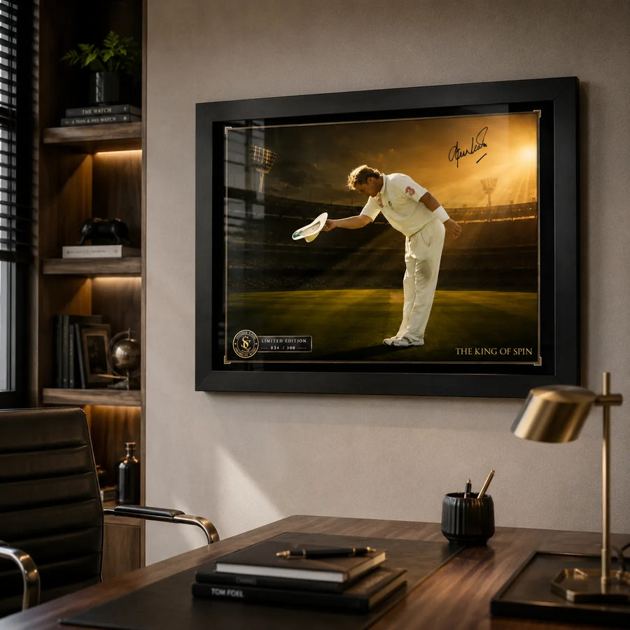 Shane Warne cricket wall art in a black frame mounted above a timber desk in a refined home office.