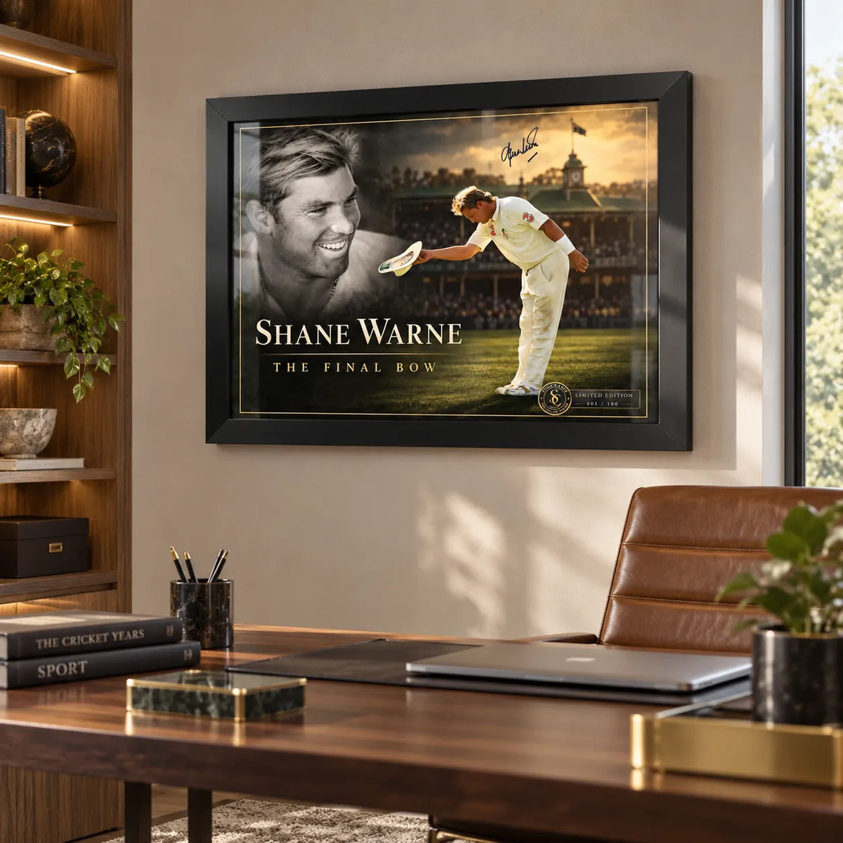 Shane Warne The Final Bow black framed cricket edition hanging above a wooden desk in a warm home office.