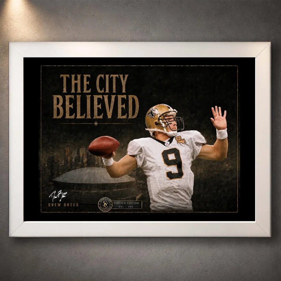 White framed The City Believed NFL wall art with a New Orleans quarterback, gold title typography and a dark stadium scene.