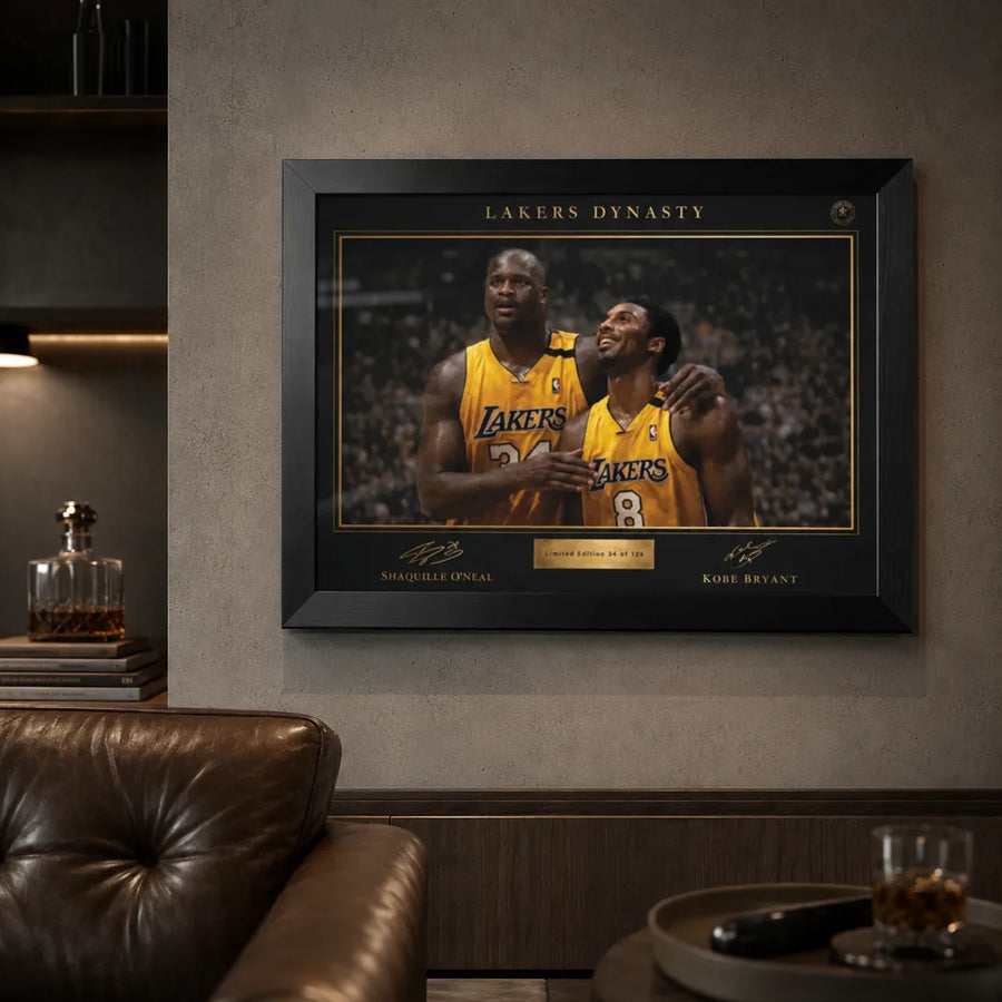 Lakers Dynasty black framed NBA wall art displayed in a premium lounge with concrete wall and leather chair.