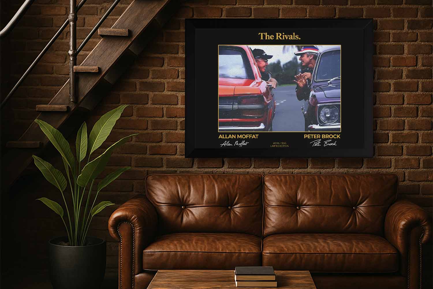 Framed “The Rivals” wall art of Peter Brock and Allan Moffat displayed in a stylish man cave with leather couch, brick wall, and warm lighting – perfect decor for motorsport fans and collectors.