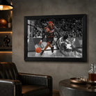 Black framed Allen Iverson crossover print displayed in a dark man cave with shelves and leather seating.
