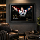 Brad Fittler wall art displayed in a dark man cave, with the black framed Roosters Legacy tribute above a leather chair.