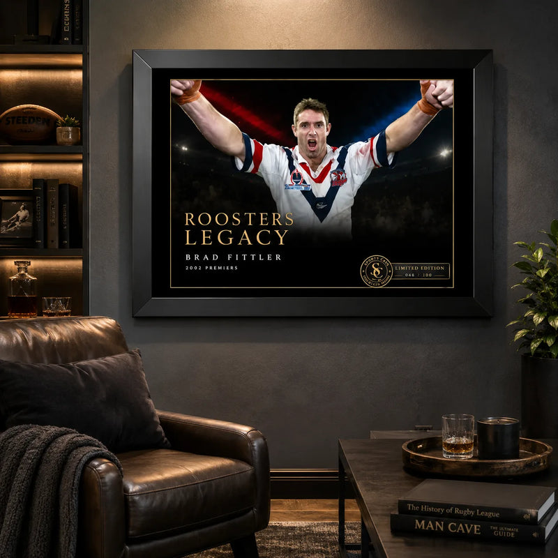 Brad Fittler wall art displayed in a dark man cave, with the black framed Roosters Legacy tribute above a leather chair.