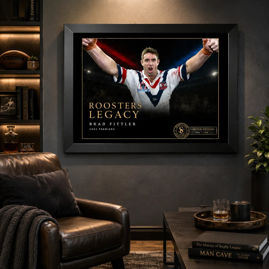 Brad Fittler wall art displayed in a dark man cave, with the black framed Roosters Legacy tribute above a leather chair.
