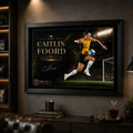 Caitlin Foord soccer wall art in a black frame displayed in a dark man cave with sports shelving and lounge seating.