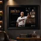 Black framed Cal Ripken Jr. baseball wall art displayed in a dark premium man cave with timber shelving.