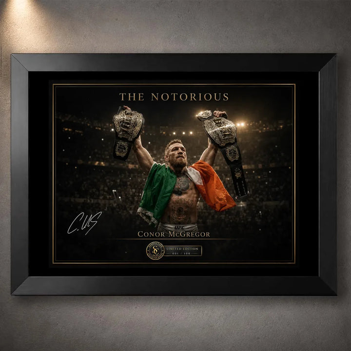 Black framed Conor McGregor wall art showing The Notorious beneath arena lights with both championship belts raised.