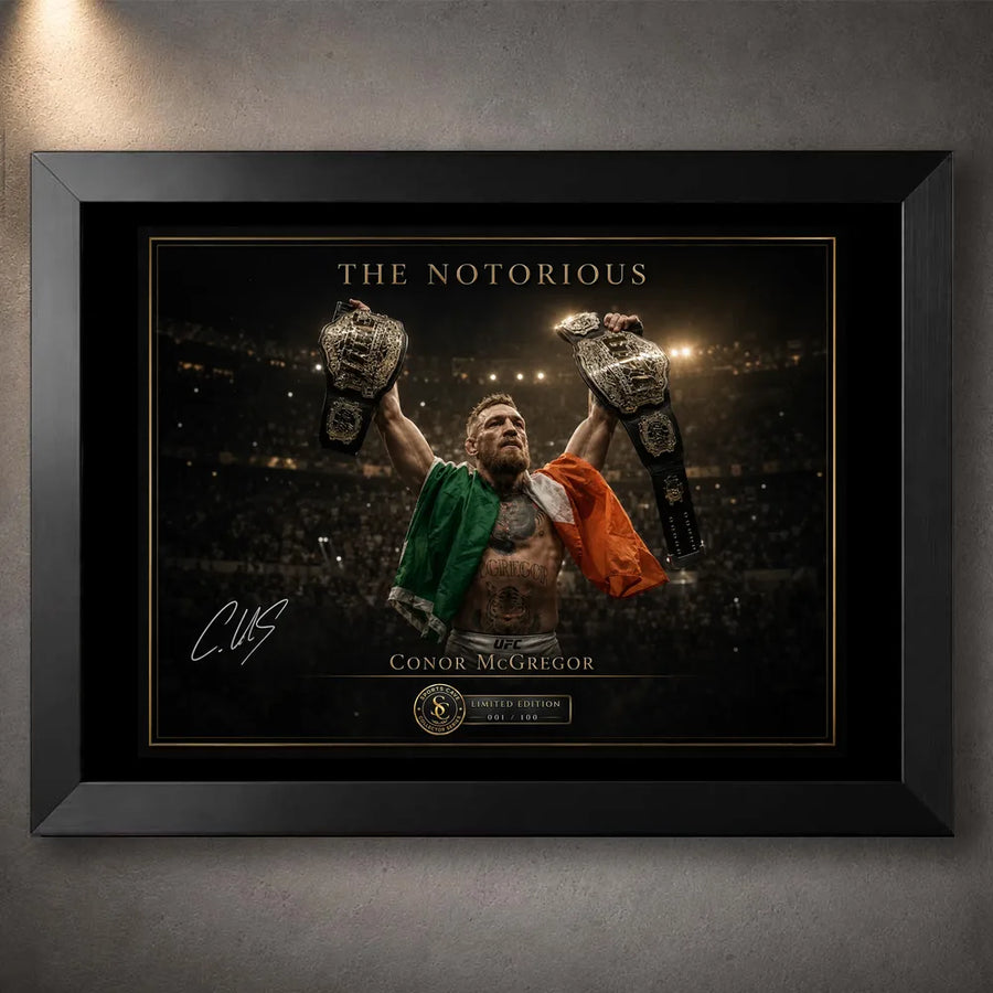 Black framed Conor McGregor wall art showing The Notorious beneath arena lights with both championship belts raised.