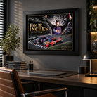 Black-framed Denny Hamlin Four Inches wall art hanging above a wooden desk in a dark modern office.