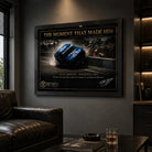 Black framed Dick Johnson Bathurst 1980 motorsport wall art displayed in a dark man cave beside leather seating.