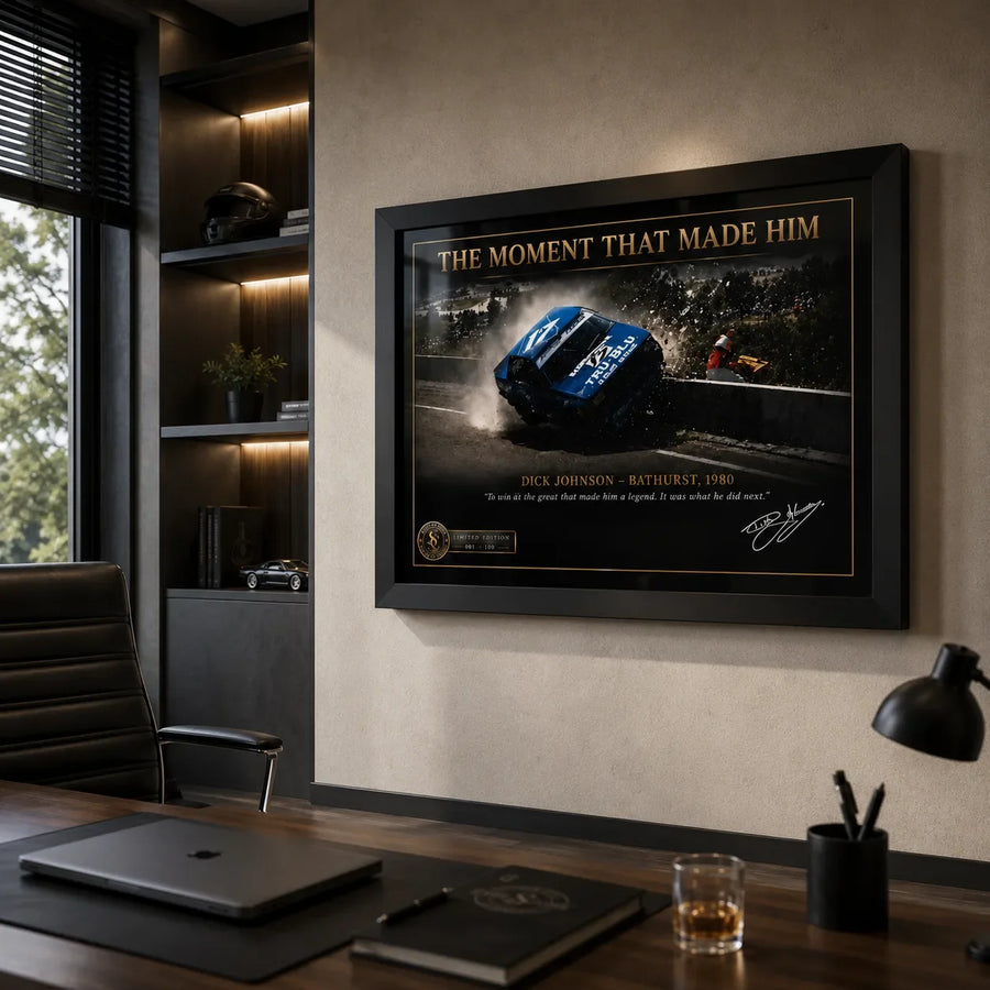 Dick Johnson Bathurst 1980 wall art mounted in a modern office above a timber desk with dark built-in shelving.