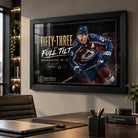 Nathan MacKinnon wall art in a modern office, black framed above a timber desk with dark shelving and warm lighting.