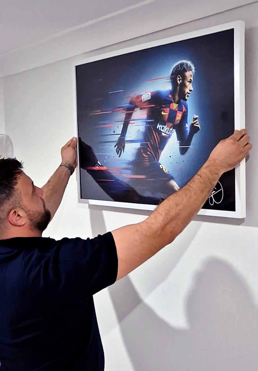 Sports Cave founder hanging sport art on wall.