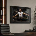 Harry Kane wall art in a black frame displayed in a modern office with timber shelving and a black leather chair.