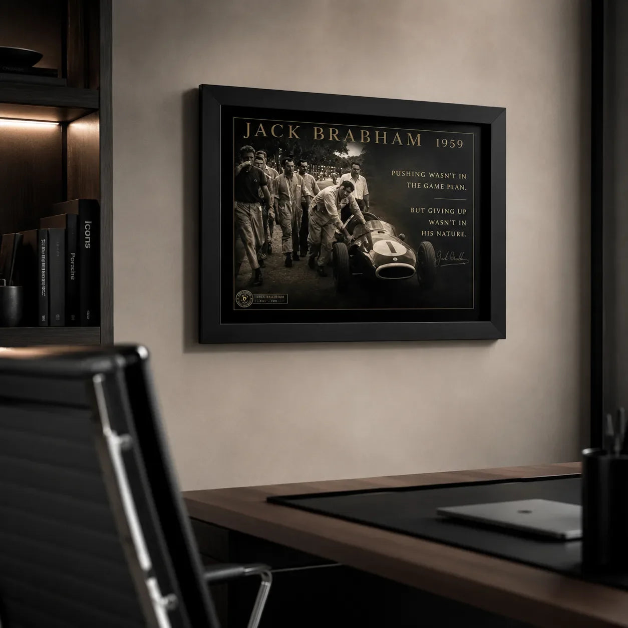 Black-framed Jack Brabham motorsport wall art displayed in a modern office above a timber desk and black chair.