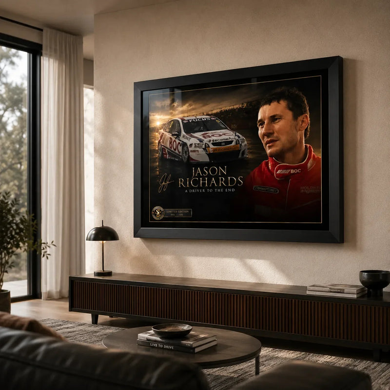 Black framed Jason Richards motorsport wall art displayed in a warm living room above a timber cabinet beside a window.