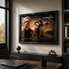 Black framed Jett Lawrence motocross wall art displayed behind a desk in a modern office with neutral walls.
