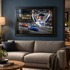 Kyle Larson The Talladega Miracle edition in a black frame above a fabric sofa against a blue living room wall.