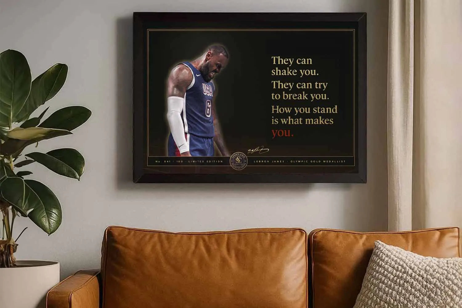 LeBron James USA motivational quote black framed NBA wall art hanging above a tan leather sofa in a modern living room.