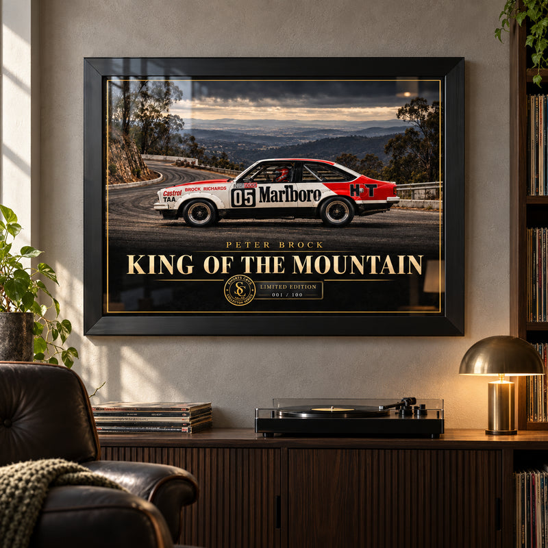 Peter Brock King of the Mountain wall art in a collector lounge above a record player, with a black frame and window reflections.