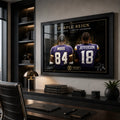 Black framed Purple Reign Randy Moss and Justin Jefferson wall art displayed above a desk in a modern office.