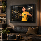 Sam Kerr Matildas soccer wall art in a black frame displayed in a dark man cave above a leather sofa and bar shelving.