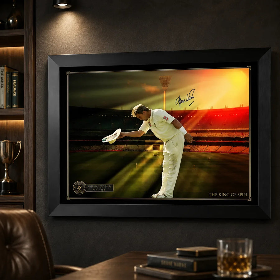Black framed Shane Warne cricket wall art displayed on a charcoal man cave wall beside warm timber shelving.