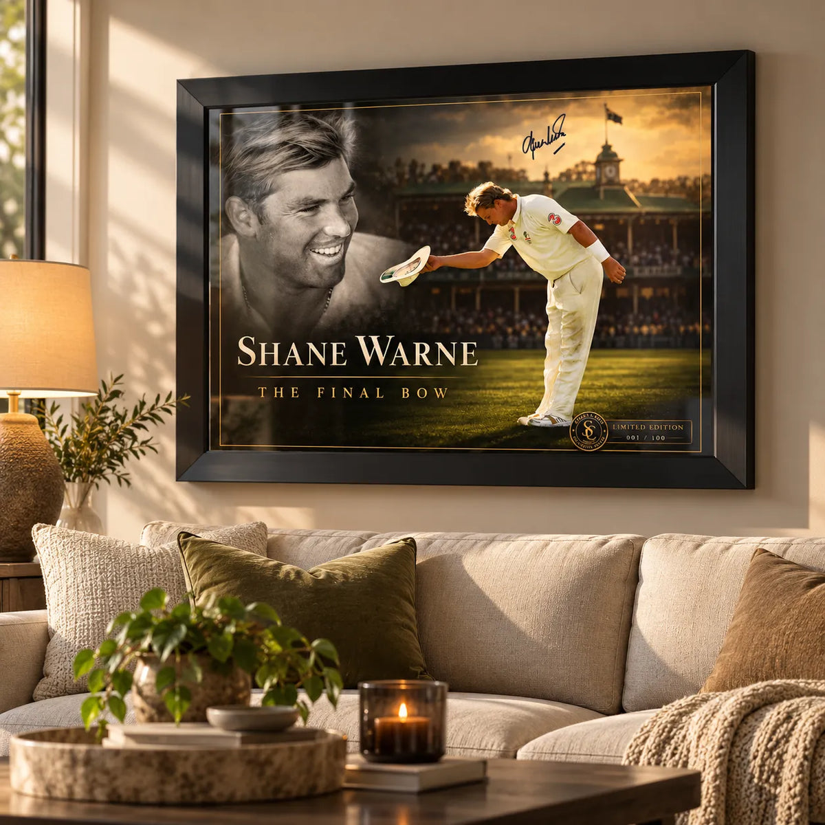 Shane Warne The Final Bow black framed cricket edition mounted above a cream sofa in a sunlit living room.