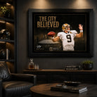 The City Believed New Orleans football wall art in a dark man cave, black framed above a cabinet with football memorabilia.