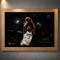 Kawhi Leonard The Claw basketball wall art in an oak frame, shown as a close-up product display on a dark grey wall.