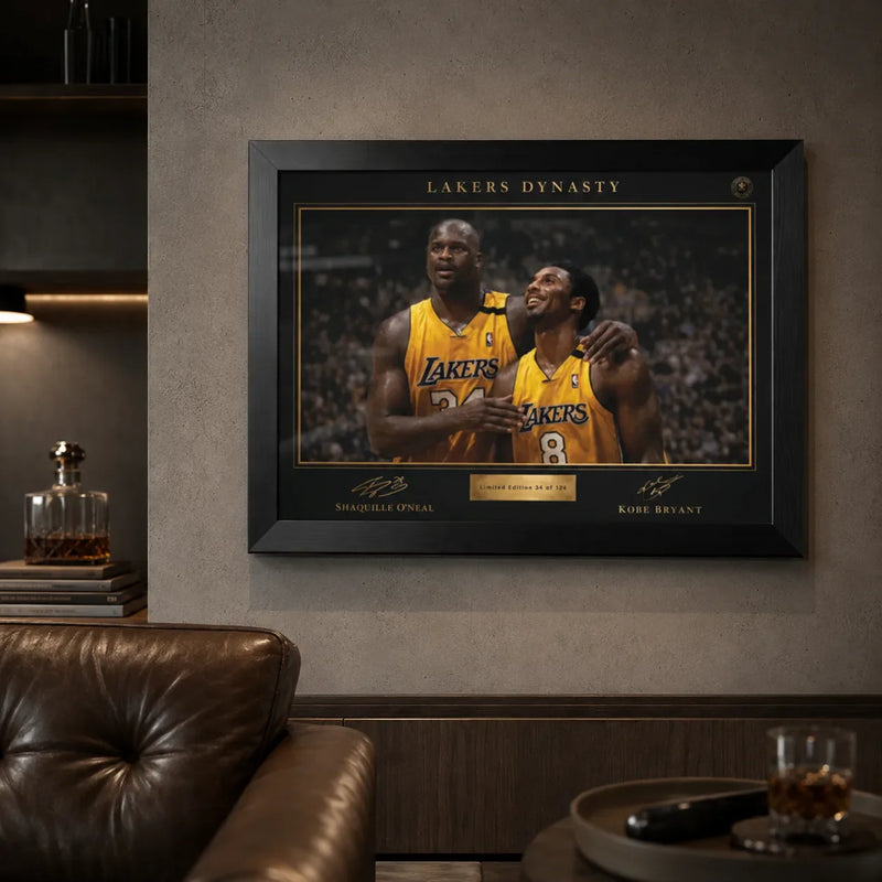 Lakers Dynasty black framed NBA wall art displayed in a premium lounge with concrete wall and leather chair.