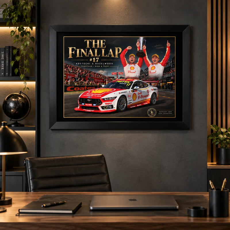 Black-framed The Final Lap #17 Bathurst wall art over a wooden desk and laptop in a dark home office with display shelves.