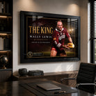 Black framed Wally Lewis wall art displayed in a modern office above a timber cabinet beside a desk and chair.
