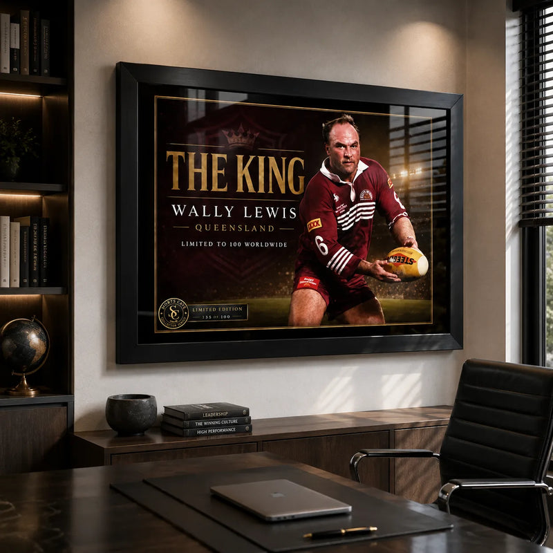 Black framed Wally Lewis wall art displayed in a modern office above a timber cabinet beside a desk and chair.