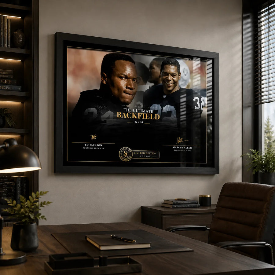The Ultimate Backfield Bo Jackson and Marcus Allen wall art displayed in a modern office above a dark wood desk.