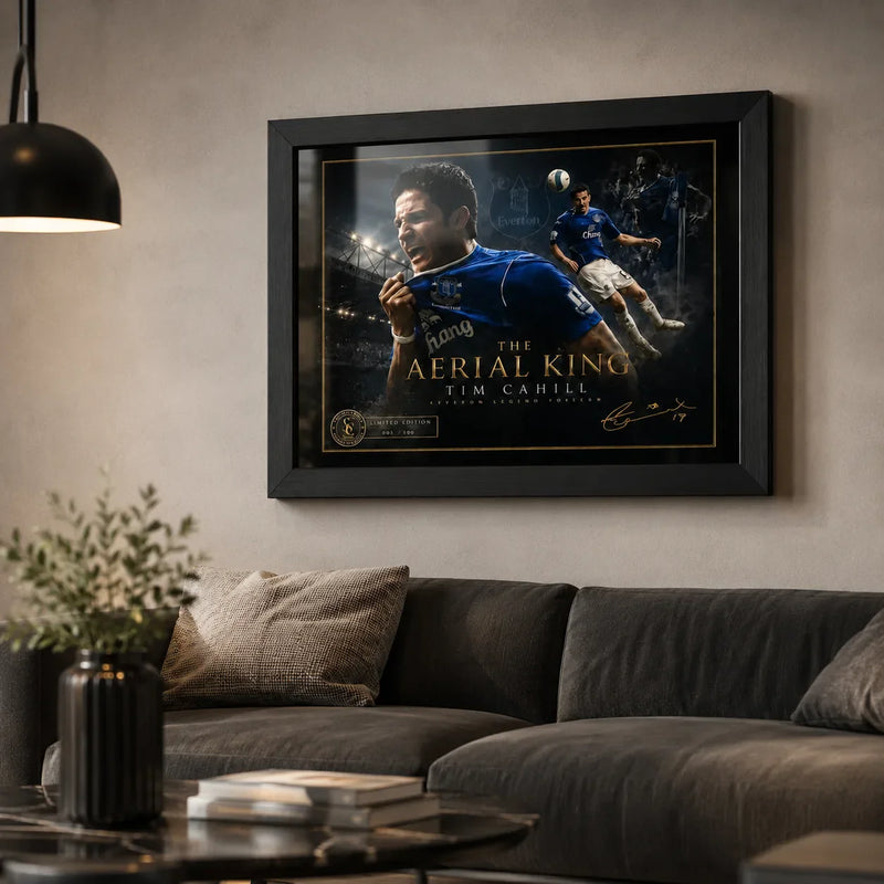Black framed Tim Cahill Everton wall art displayed above a dark sofa in a premium living room setting.